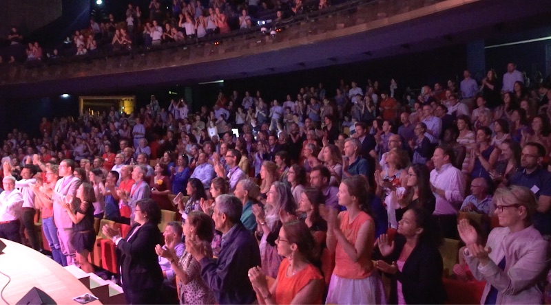 Le public debout applaudit dans une salle de concert