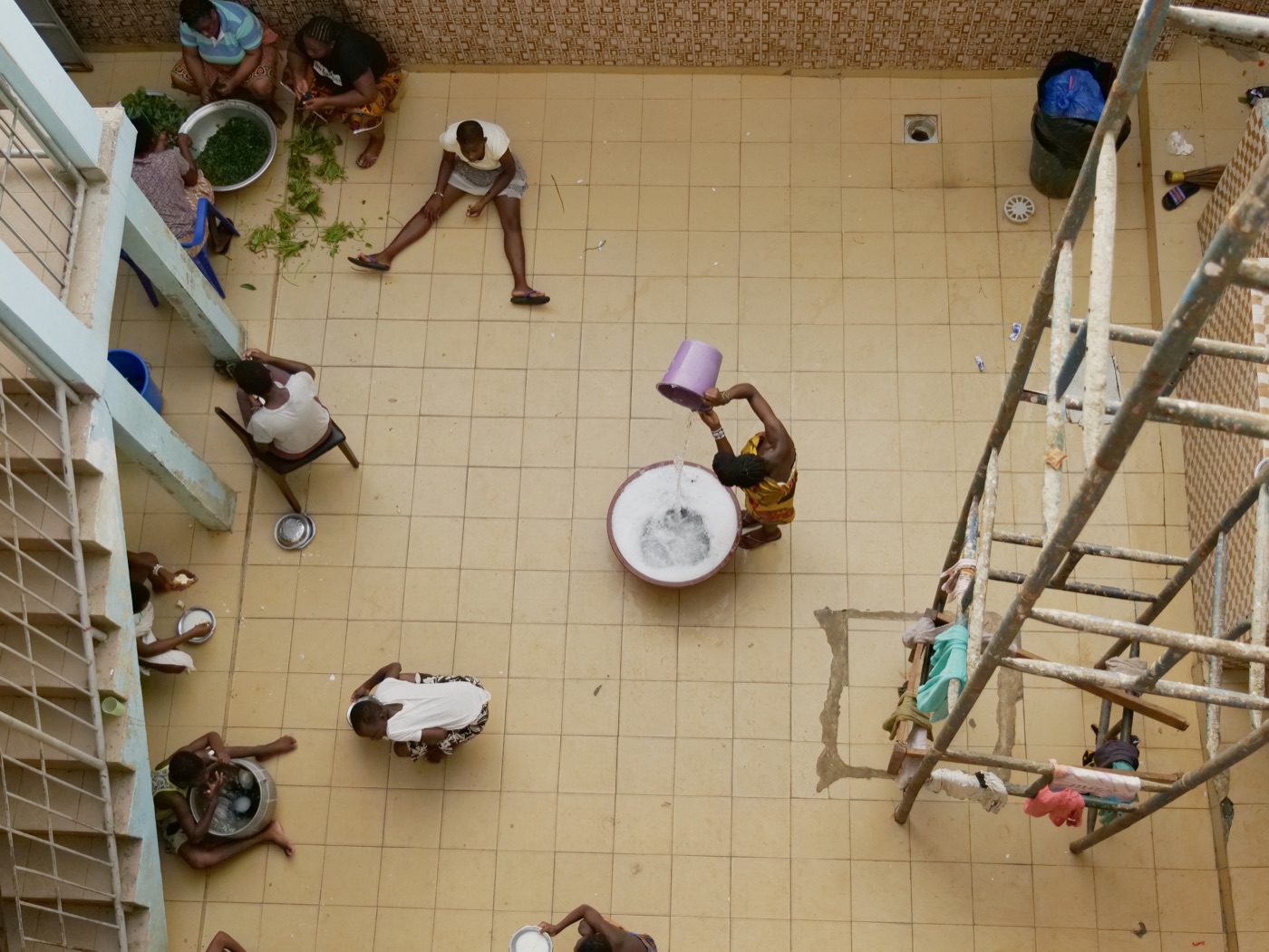 Vue plongeante sur la cour du centre, à Abidjan : des femmes préparent le repas
